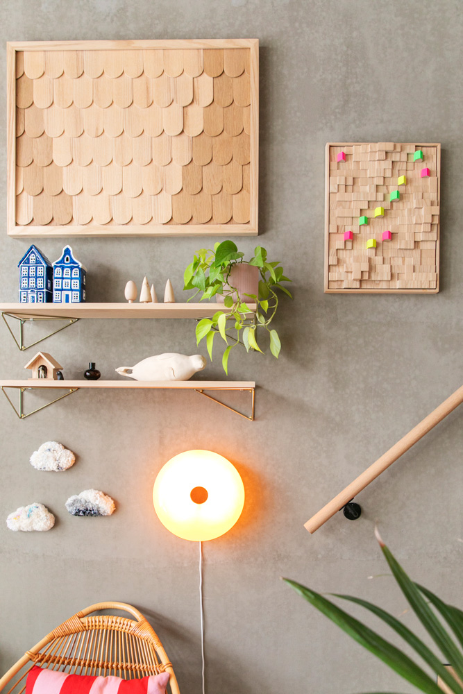 Muotoilija Jenni Pehkosen työhuoneen harmaa betoniseinä, jolla on puisia reliefitaideteoksia ja hyllyjä. Seinällä on suuri puinen paanukuvioinen teos ja pienempi puukuutioista koostuva reliefi neonvärisillä yksityiskohdilla. Hyllyillä on koriste-esineitä, kuten sinivalkoisia taloja ja hylje-veistos. Kokonaisuuden täydentävät pyöreä valaisin, rottinkituoli ja viherkasvi.